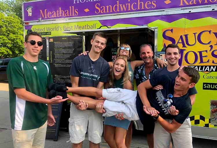 Graduate at party with family having a great time in front of a Food Truck