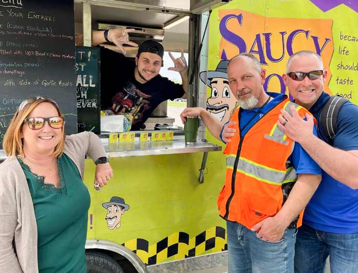 Employees smiling in front of food truck at staff appreciation