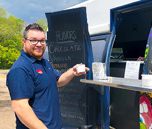 Happy guy getting gelato from dessert truck at office party