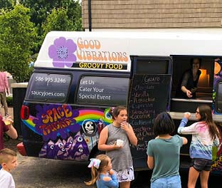 Girls getting ice cream from dessert truck at outdoor party