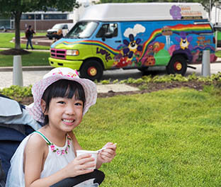 Girl smiling and eating ice cream in park from Gelato Truck